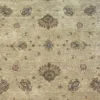 Macro shot of the hand-spun wool pile on a sage Chobi rug showing muted tan floral motifs and natural abrash color variations.