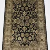 Full overhead view of a 5' 11" x 9' hand-knotted Indian wool rug featuring a symmetrical floral design on a black field with a wide olive-gold border.