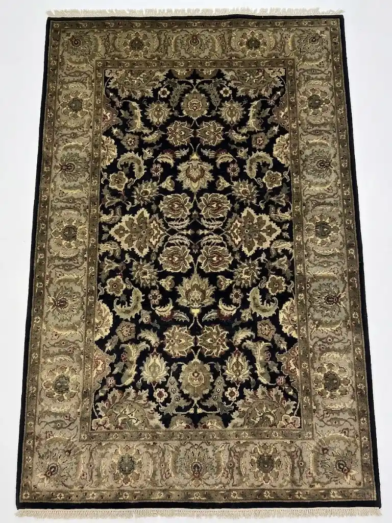 Full overhead view of a 5' 11" x 9' hand-knotted Indian wool rug featuring a symmetrical floral design on a black field with a wide olive-gold border.