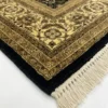 Detailed corner view of a black Indian rug showing the ornate gold-tan botanical border and clean white hand-bound fringe.