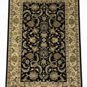 Full overhead view of a 5' x 8' hand-knotted Indian wool rug featuring a saturated black field with large-scale scrolling floral vines and an ornate ivory-tan border.
