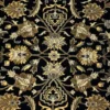 Macro shot of the dense hand-knotted wool pile showing intricate sage green and tan floral motifs on a deep black background.