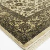 Detailed corner view of a black Indian rug showing the ornate olive-gold botanical border and clean white hand-bound fringe.