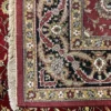 Close-up view of the underside of a red Indian wool rug, showing the visible individual hand-tied knots and authentic textile construction.