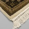 Detailed corner view of a white Indian rug showing the ornate botanical border and clean white hand-bound fringe.