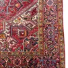 Detailed corner view of a red Persian Heriz rug showing the ornate botanical border and secure hand-bound edges.