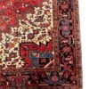 Detailed corner view of a red and indigo Persian Heriz rug showing the multi-layered botanical border and secure hand-knotted edges.