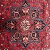 Macro shot of the dense hand-knotted wool pile on a Heriz rug showing the central geometric star and intricate indigo and cream floral details.