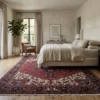 Bright minimalist bedroom with neutral linens and a wooden bed frame, anchored by a large 8x11 Persian Heriz rug under the bed.