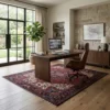 Professional home office with a dark wood desk and built-in library shelves, featuring a large red Persian Heriz rug on hardwood floors.