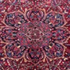 Macro shot of the dense hand-knotted wool pile on a Heriz rug showing the central star medallion with intricate indigo and terracotta geometric details.
