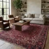 Expansive living room with light walls and a minimalist sofa, anchored by a large red and indigo Persian Heriz rug on light wood floors.