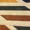 Macro shot of the thick tufted wool pile showing the central medallion details in navy and crimson on a luminous cream background.
