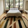 Warm modern bedroom with a wooden bed frame and neutral linens, featuring a 6x9 cream and navy tufted wool rug providing a bright foundation.