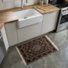 Modern kitchen with a white farmhouse sink and butcher block countertops, featuring a small hand-knotted Indian wool rug as a functional accent on a gray concrete floor.