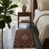 Serene bedroom with dark concrete floors and a walnut nightstand, featuring a small hand-knotted Indian wool rug placed at the foot of the bed.