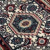 Macro shot of the dense hand-knotted wool pile showing the central hexagonal medallion with intricate blue, ivory, and burgundy details.