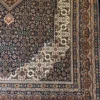 Detailed corner view of a charcoal and bronze Indian wool rug highlighting the stepped ivory corner spandrel and precise multi-layered geometric border.