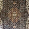 Close-up macro shot of the dense hand-knotted wool pile showing intricate geometric floral patterns in copper, bronze, and charcoal.