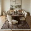 Elegant dining room featuring a long walnut table and cream upholstered chairs, centered over a 6x10 charcoal and cream hand-knotted wool rug.