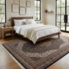 Peaceful primary bedroom with a mid-century walnut bed frame and white linens, anchored by an intricate charcoal and cream Indian area rug on light wood floors.