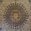 Macro shot of the dense hand-knotted wool pile on an Iranian Birjand rug, showcasing the radiating copper and navy patterns of the central medallion.