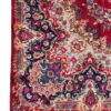 Detailed corner view of a red Iran Darbari rug showing the ornate botanical border and secure hand-knotted edge finish.