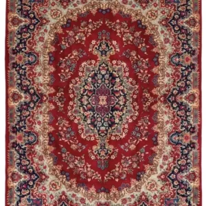 Full overhead view of an 8' 2" x 11' 5" hand-knotted Iran Darbari wool rug featuring a large navy and ivory medallion on a saturated red field with an intricate floral border.