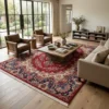 Elegant living room with large windows, neutral sofas, and brown leather chairs, anchored by a large red Iran Darbari wool rug on hardwood floors.