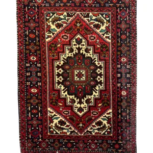 Overhead view of a 1' 10" x 2' 6" hand-knotted Iranian Gholtogh wool rug featuring a vibrant blue hexagonal medallion on a saturated red field.