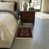 Peaceful modern bedroom featuring a walnut nightstand and light linens, with a small red and navy Gholtogh Persian rug providing a warm tactile accent on gray floors.