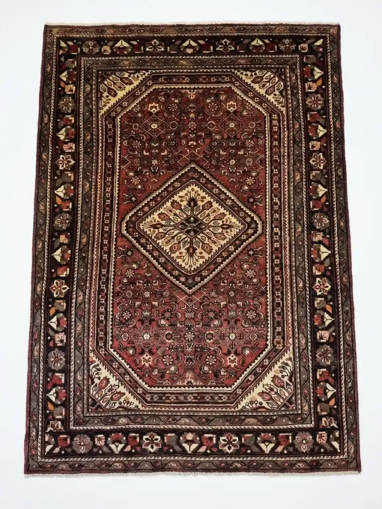 Full overhead view of a 6' 10" x 10' 4" hand-knotted Iranian Hosinabad wool rug with a sharp cream and red central diamond medallion.