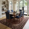 Sophisticated dining room with a long wooden table and navy blue upholstered chairs, centered over an intricate 7x10 Hosinabad Persian area rug.