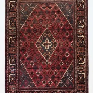 Full overhead view of a 7' 0" x 10' 0" hand-knotted Iranian Joshaghan wool rug with an intricate geometric diamond medallion on a saturated red and navy field.