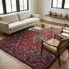 Bright transitional living room with a green tufted leather sofa and oak coffee table, highlighted by a traditional red Persian Joshaghan rug.