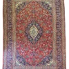 Full overhead view of a 6' 4" x 9' 6" hand-knotted Iranian Kashan wool rug with a detailed diamond medallion on a crimson field with navy borders.