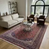 Luminous contemporary living room with a cream sofa and glass coffee table, anchored by a 6x10 red and navy Kashan Persian rug on light wood floors.