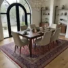 Sophisticated dining room featuring a long wooden table and beige upholstered chairs, centered over an intricate 6x10 Kashan area rug.
