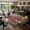 Modern coffee shop and library with a dark wood bar and seating areas, anchored by a large red Persian Kashan rug on light wood floors.
