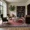 Bright living room with large windows, a brown leather sofa, and green wingback chairs, anchored by a large 10x13 Persian Kashan rug.
