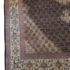 Close-up of the corner of a brown and white Persian Mahi rug showcasing the tightly bound selvedge and clean white fringe finish.