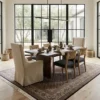 Minimalist modern dining room featuring a long wooden dining table and sleek contemporary chairs, centered over a brown and white hand-knotted Persian Mahi area rug.