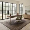 Modern home library/office with built-in bookshelves and a walnut desk, anchored by a long brown and white Persian Mahi wool rug on concrete floors.