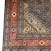 Close-up corner view of a blue and orange Persian Mahi rug highlighting the intricate multi-guard borders and precise hand-bound edge finish.