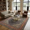Luminous contemporary living room with a beige sofa and glass coffee table, anchored by a 6x10 blue, orange, and yellow Persian Mahi area rug on light wood floors.