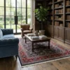 Professional home library with full-height walnut shelving and a blue velvet sofa, anchored by a navy Persian Mood rug.