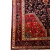 Technical corner view of a Persian Nahavand rug showing the dense geometric outer borders, rich red field corner, and hand-bound edges.