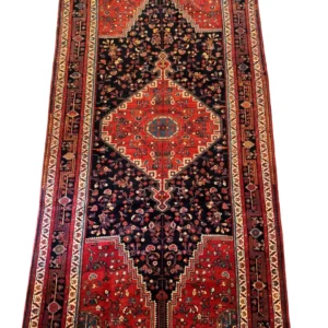 Full overhead view of a 5' 3" x 10' 9" hand-knotted Iranian Nahavand wool rug with a large terracotta-red diamond medallion on a dense midnight navy field.
