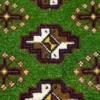 Macro shot of the dense hand-knotted wool pile on a green Persian rug showing the intricate geometric motifs and rich, saturated vegetable-dye colors.