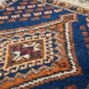 Macro shot of the dense hand-knotted wool pile on a navy Qashqai rug showing the intricate geometric motifs and rich burnt orange vegetable-dye colors.